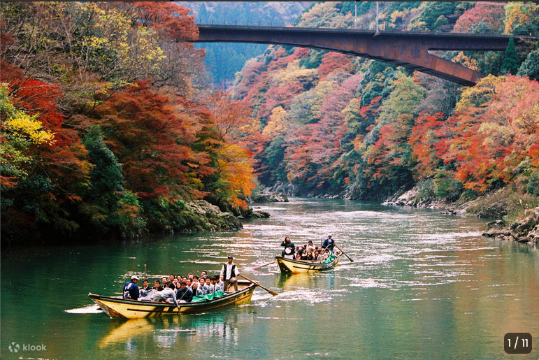 Traditional wooden boats on the Hozugawa River surrounded by vibrant autumn foliage in Kyoto
